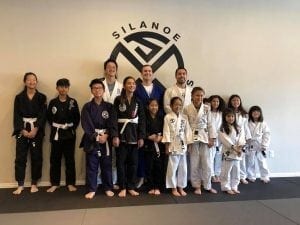 The kids and teen students lined up in front of the wall at the Silanoe Martial Arts logo. The kids have learned how to defend against bullying.