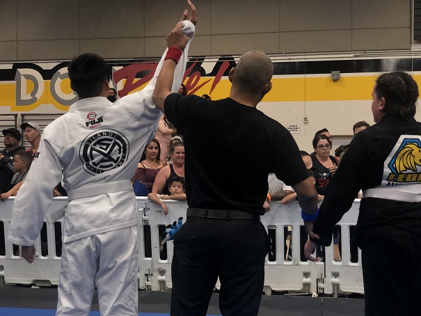 Avery's first BJJ competition match ends in a win as his hand is being raised.