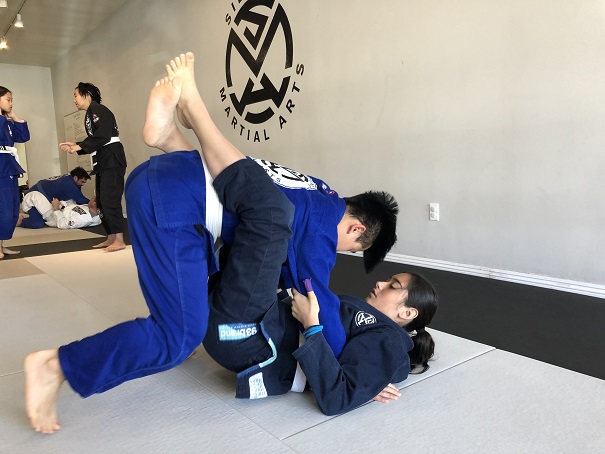 Ally on bottom position and Ethan on top working from the closed guard in Brazilian Jiu-Jitsu.